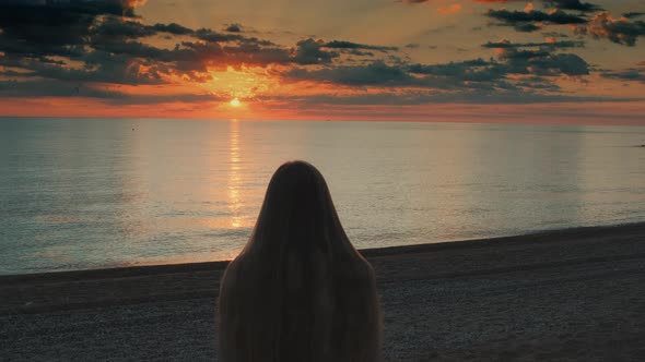 Woman Walking To the Sea and Raising Her Hands Up