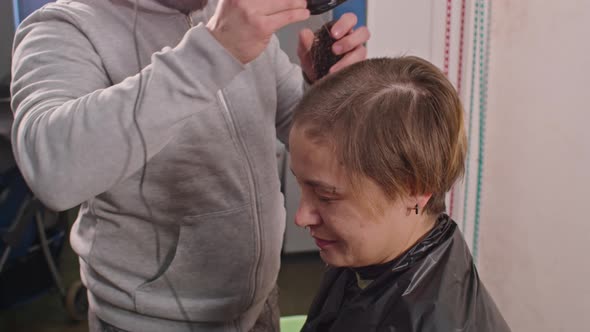 an Adult Man Cuts a Sad Woman Bald with a Typewriter