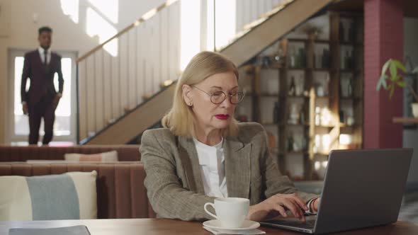 Senior Businesswoman Using Laptop in Restaurant