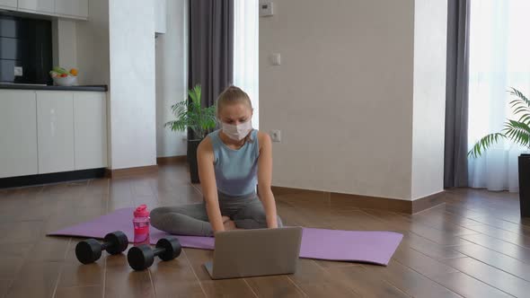 Athletic Woman in Mask Using Laptop for Workout at Home