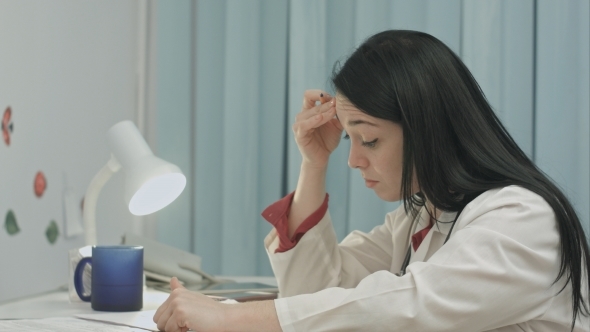 Tired Female Doctor Sits In a Medical Office alt
