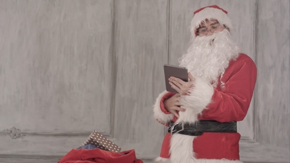 Santa Claus With Tablet Pc Computer Checking Gift