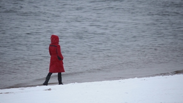 A Girl Walks Along the Riverbank in Winter