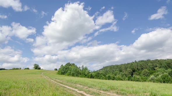 Clouds Moving over Green Field and Country Road