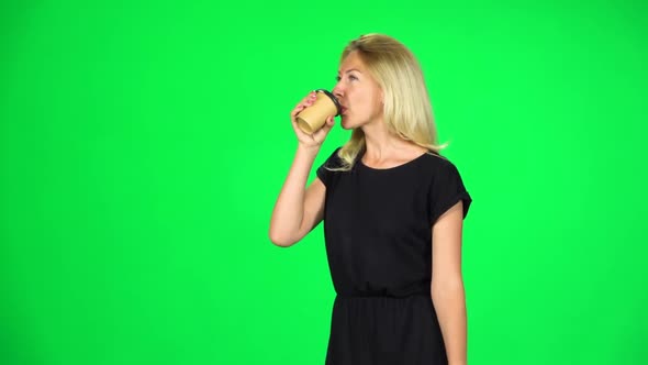 Blonde Girl Is Walking and Drinking Coffee From a Paper Cup. Chroma Key. Slow Motion