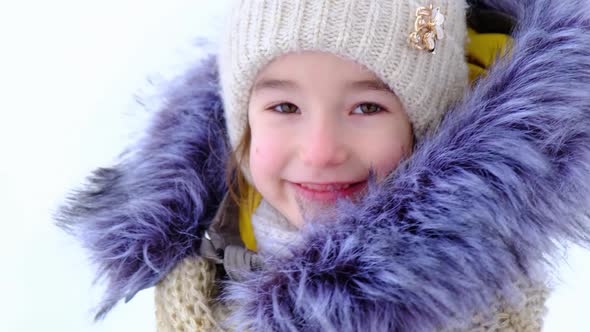 Portrait of a cheerful and happy 5-year-old girl in close-up in winter warm clothes
