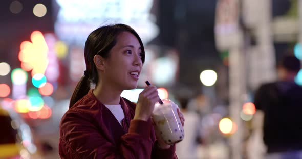 Woman enjoy iced bubble tea in city at night