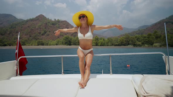 Beautiful Woman Wearing Straw Hat and White Bikini on a Yacht Enjoys the Journey