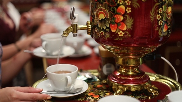 Woman Pours Boiling Water from the Samovar into a Cup