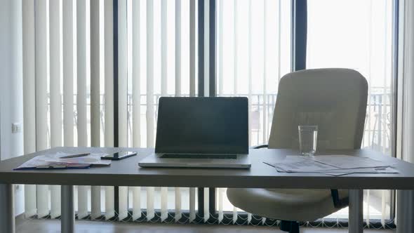 Desk with a Laptop on It in Modern Office Over Big Windows