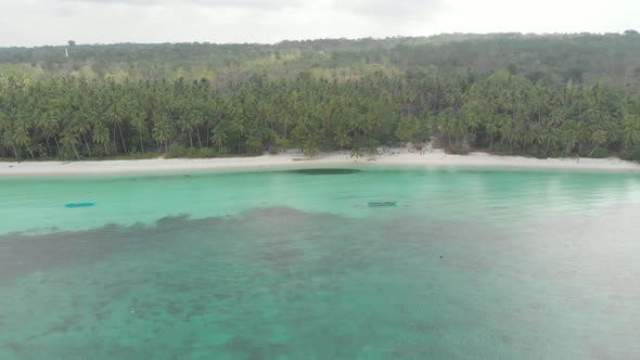 Aerial: flying over white sand beach tropical sea village Kei Islands Indonesia