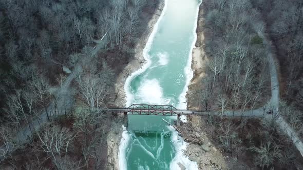 Rusty Footbridge over Icy Mountain River