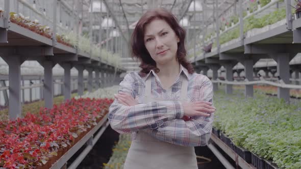 Portrait of Confident Positive Woman Posing in Greenhouse. Mid-adult Brunette Employee Agronomist