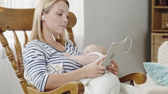 Mother Listening to Music while Rocking Baby Son alt