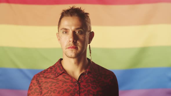 Cheerful Gay Man with Makeup Posing against LGBT Flag