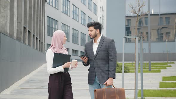 Muslim Businessman in Suit Showing Something on Smartphone to His Female