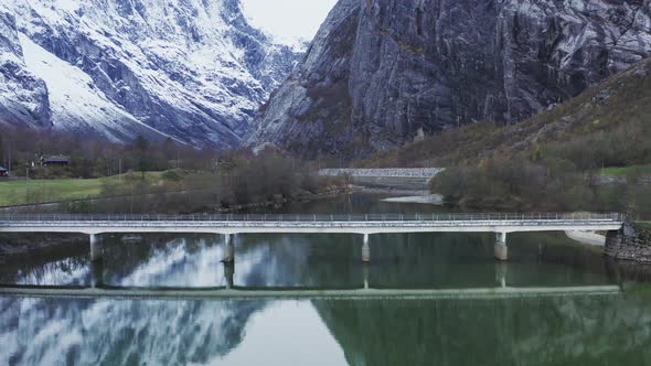 Bridge Over Rauma River With Snowy Trollveggen Mountain Massif In Andalsnes, Norway. - aerial