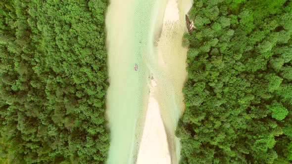 Aerial view of adventurers doing rafting surrounded by a big green forest.