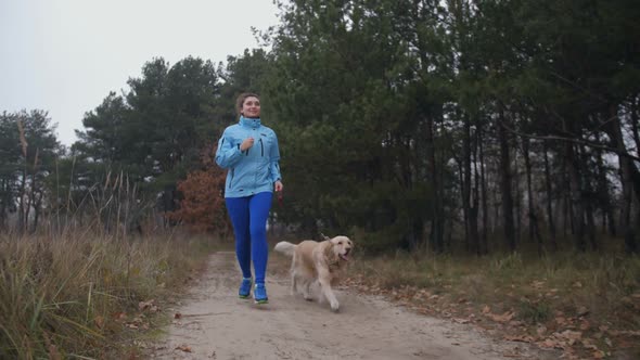 Sporty Fit Woman with Dog Jogging in Autumn Forest