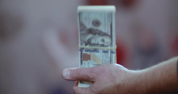 Slow motion close-up of a person flapping around a bundle of prop money with a rubber band on it.