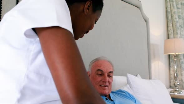 Nurse examining senior man on bed