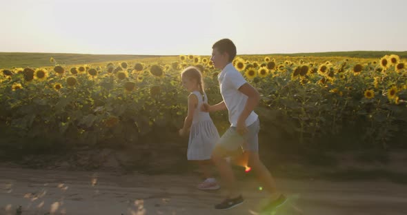 Little Boy And Girl Are Running Across The Field