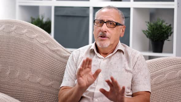 Friendly 70s Grandfather Talking Looking at Camera in Home Video Call