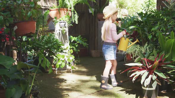 Little girl gardening and watering plant in a botanical garden