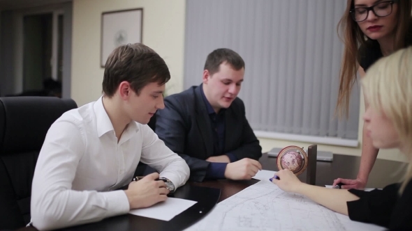 Team Of Engineers Discussing Blueprint At Meeting