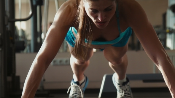 The Woman In Sportswear Does Push-ups In a Gym