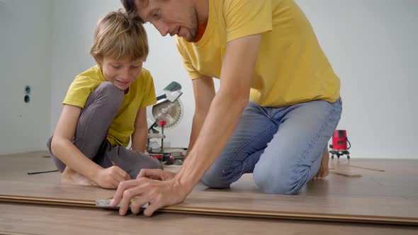 Father and His Little Son Install Laminate on the Floor in Their Apartment