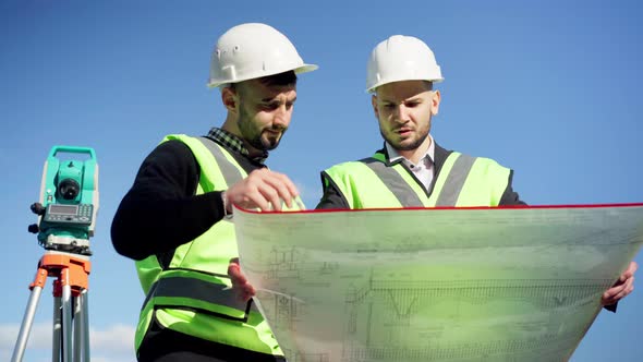 Front View Two Expert Architects Talking Analyzing Blueprint Standing in Sunbeam Outdoors