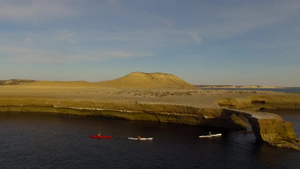 Tourists kayak through a rock formation along the coast of Peninsula Valdes, Chubut Province, Argent