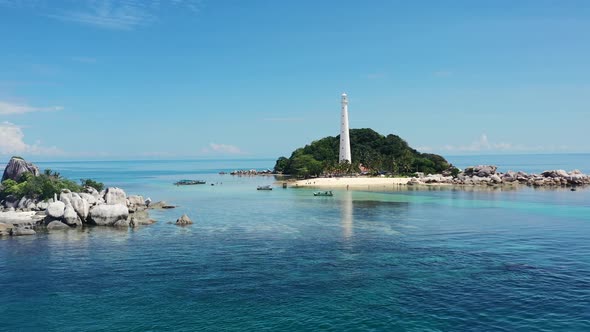 aerial drone of Kepayang Island in Belitung Indonesia with a large white lighthouse surrounded by fo