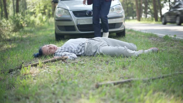 Wide Shot Knocked Down Woman Lying on Roadside with Man Walking Out the Car Checking Corpse Pulse