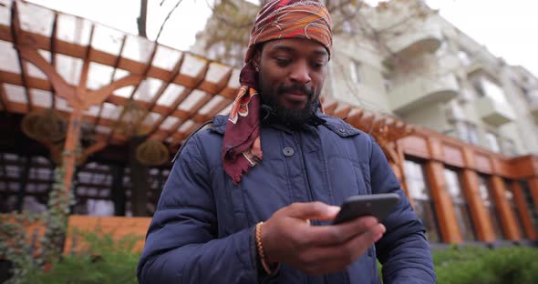 African American Man Using Mobile Phone in the City Street