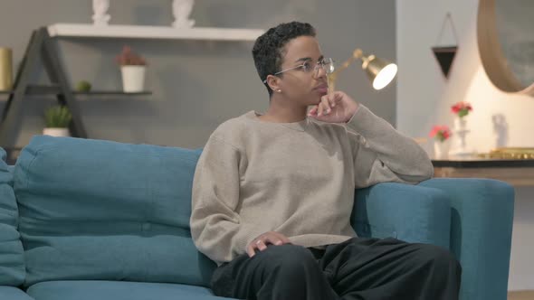 African Woman Thinking While Sitting on Sofa