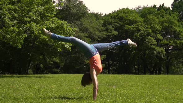 Young Girl Gets on Her Hands Doing Splits in the Green Park Day