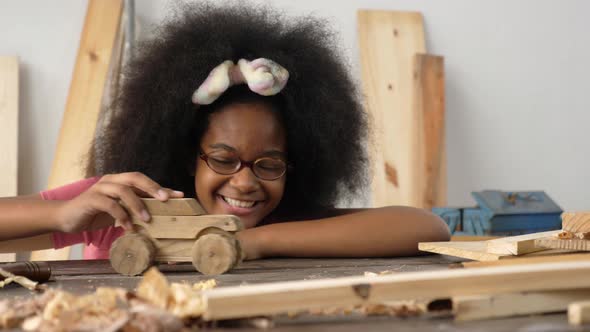 African girl playing with wooden toy car. Carpenter and craftmanship concept.