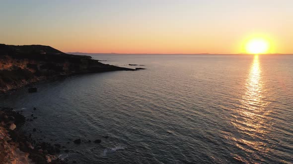 Ascending aerial panoramic drone view at sunset of miditerranean sea of Sardinia, Italy