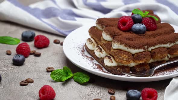 Portion of Classic Tiramisu Dessert with Raspberries and Blueberries on Grey Concrete Background