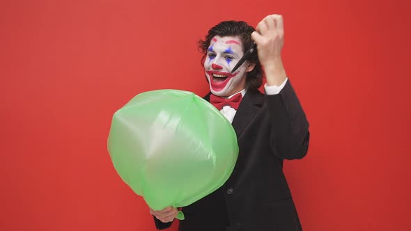 An Unusual Strange Magician Holding an Inflated Balloon on a Red Background a Magician in a Black
