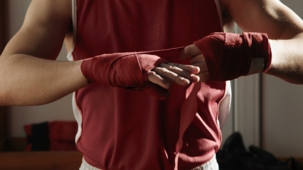 The Young Boxer Pulls Red Bandage on Hands