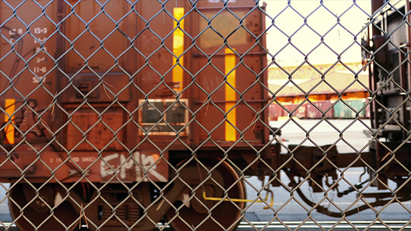Train Carriages Passing Behind Chain Link Fence