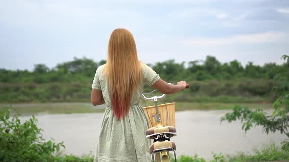 Young woman with bicycle walking on the park