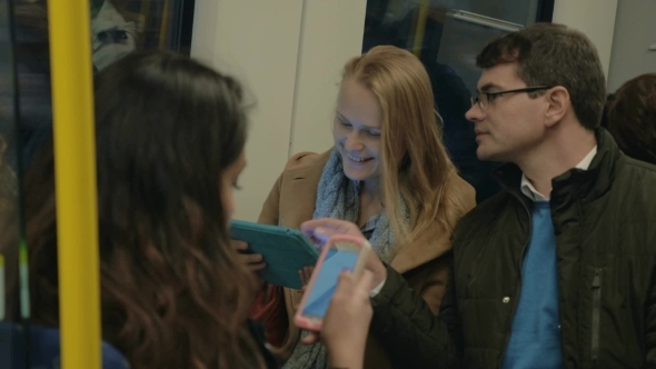 Commuters Using Pad And Cell In Metro Train