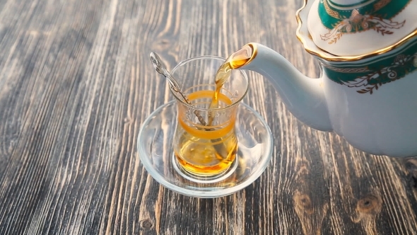 Pouring Tea Into a Cup On a Wooden Table