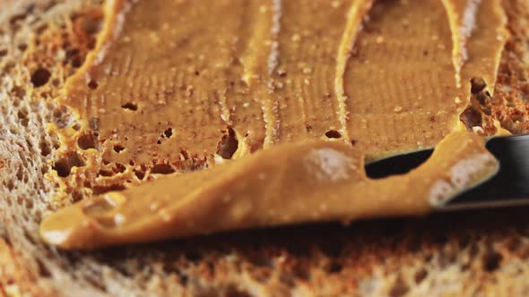 Spreading creamy peanut butter on whole wheat toast