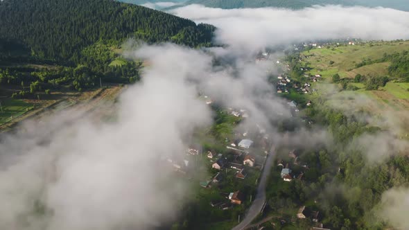 Aerial View White Fog Over Green Pine Forest on Mountains and Village Houses