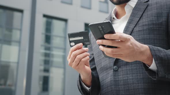 Close Up of Male Hands Holding Modern Smartphone and Credit Card